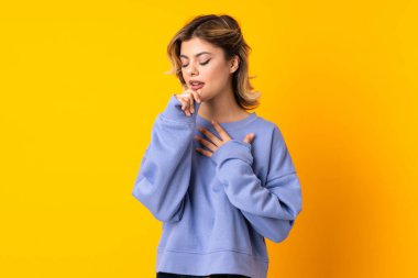 Sarı arka planda izole edilmiş genç Rus kadın çok öksürüyor.