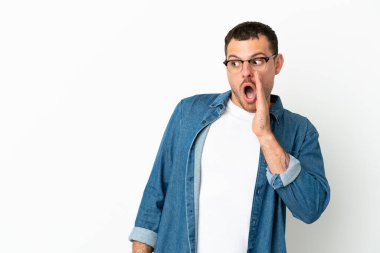 İzole edilmiş beyaz arka planda Brezilyalı bir adam yan tarafa bakarken sürpriz bir hareketle bir şeyler fısıldıyor