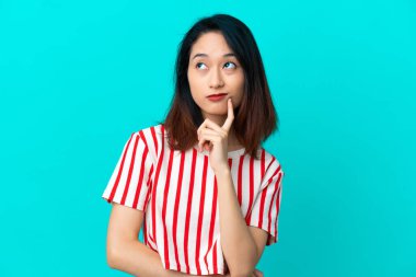 Genç Vietnamlı kadın mavi arka planda izole edilmiş.