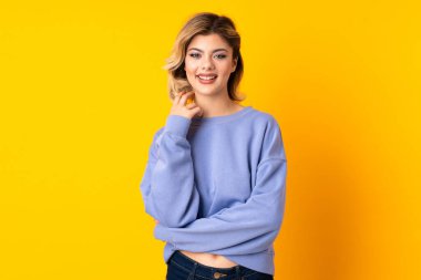 Sarı arka planda yalnız yaşayan genç Rus kadın gülüyor.