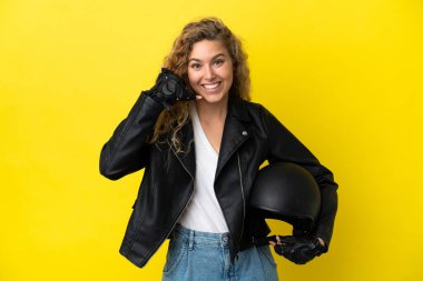 Sarı arka planda izole edilmiş motosiklet kasklı genç sarışın bir kadın telefon jesti yapıyor. Bana geri dönüş işareti ver.