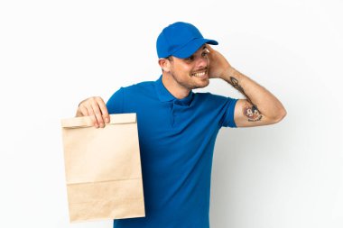 Brezilyalı, beyaz arka planda izole edilmiş bir paket yiyecek alıyor. Kulağına elini sürerek bir şey dinliyor.