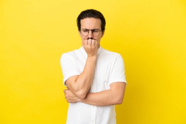 Sarı arka planda izole edilmiş genç beyaz adamın şüpheleri var.