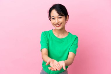 Pembe arka planda izole edilmiş genç Vietnamlı bir kadın bir ilan vermek için avucunun içinde hayali bir fotokopi makinesi tutuyor.