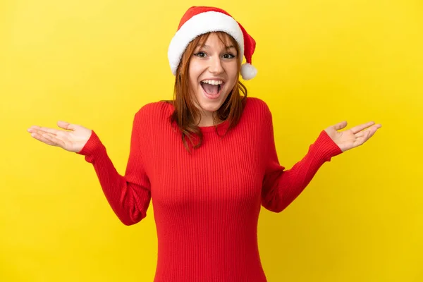 红头发姑娘 头戴一顶黄色背景的圣诞帽 满脸震惊 — 图库照片