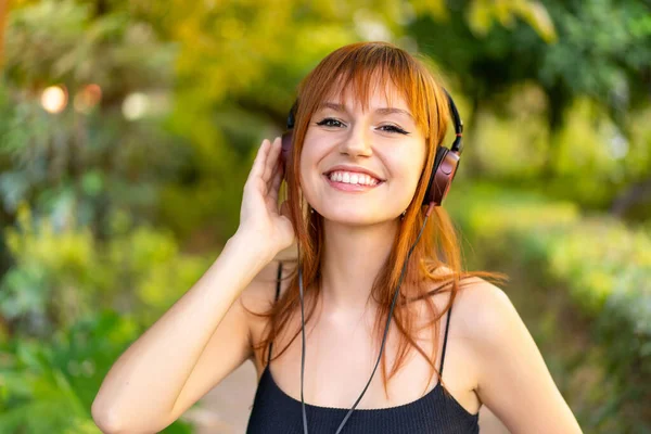 Mladý Pěkný Ryšavý Žena Outdoors Poslech Hudba — Stock fotografie