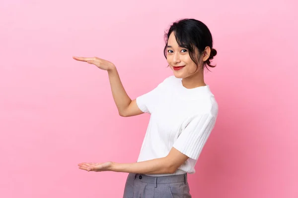 在粉色背景上被隔离的年轻越南妇女 手持版权插入广告 — 图库照片