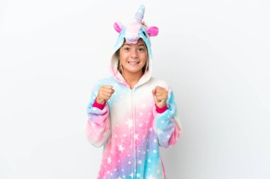 Beyaz arka planda tek boynuzlu at pijaması giyen küçük kız galibiyetini kutluyor.