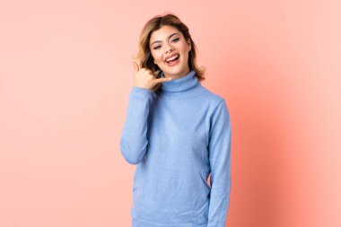 Pembe arka planda izole edilmiş genç bir Rus kadın telefon hareketi yapıyor. Bana geri dönüş işareti ver.