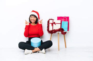 Genç kız Noel 'i kutluyor. Beyaz fırında izole bir şekilde yerde oturuyor.