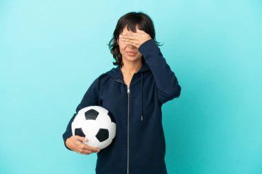 Genç melez futbolcu kadın mavi arka planda tek başına, gözleri elleriyle kapatıyor. Bir şey görmek istemiyorum.