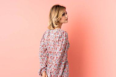 Genç Rus kadın pembe arka planda izole edilmiş ve arkasına bakıyor.