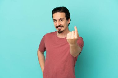 Genç beyaz adam mavi arka planda izole edilmiş bir şekilde geliyor.