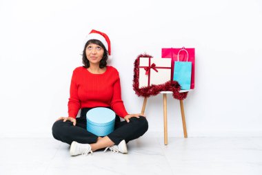 Genç bir kız Noel 'i kutluyor. Yerde izole bir şekilde oturuyor ve yukarı bakıyor.