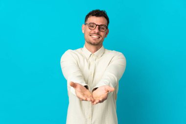 Beyaz tenli yakışıklı, mavi arka planda izole edilmiş bir adam. Elinde bir ilan vermek için fotokopi odası hayali var.