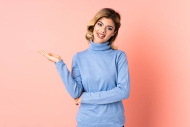 Pembe arka planda izole edilmiş genç bir Rus kadın, bir ilan vermek için avucunda hayali fotokopi makinesi tutuyor.