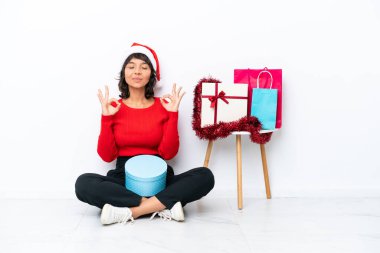 Genç bir kız Noel 'i kutluyor. Zen pozuyla beyaz bir fırında yerde tek başına oturuyor.