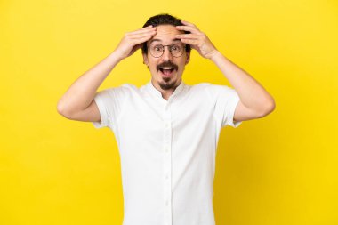 Sarı arka planda, sürpriz bir ifadeyle izole edilmiş beyaz bir genç.