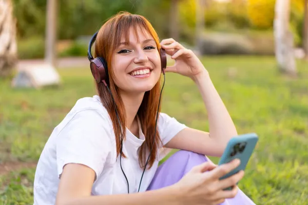Mladý Pěkný Ryšavý Žena Outdoors Poslech Hudba Mobilní — Stock fotografie