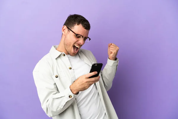 Hombre Brasileño Sobre Fondo Púrpura Aislado Con Teléfono Posición Victoria —  Fotos de Stock