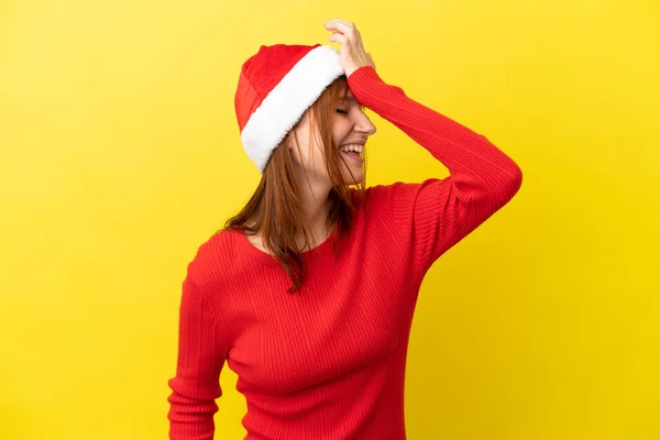 红头发姑娘带着一顶黄色背景的圣诞帽 意识到了什么 并打算解决这个问题 — 图库照片