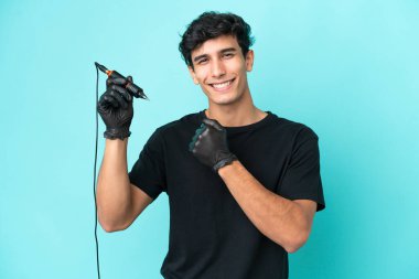 Dövme sanatçısı Arjantinli adam mavi arka planda zaferi kutluyor.