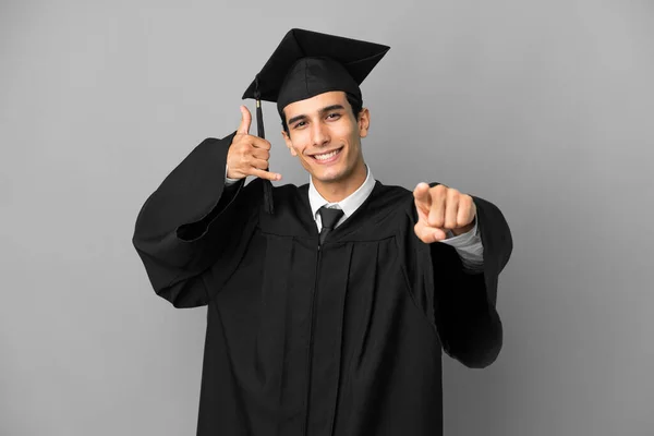年轻的阿根廷大学毕业生在灰色背景下孤立无援 一边打手势一边指路 — 图库照片