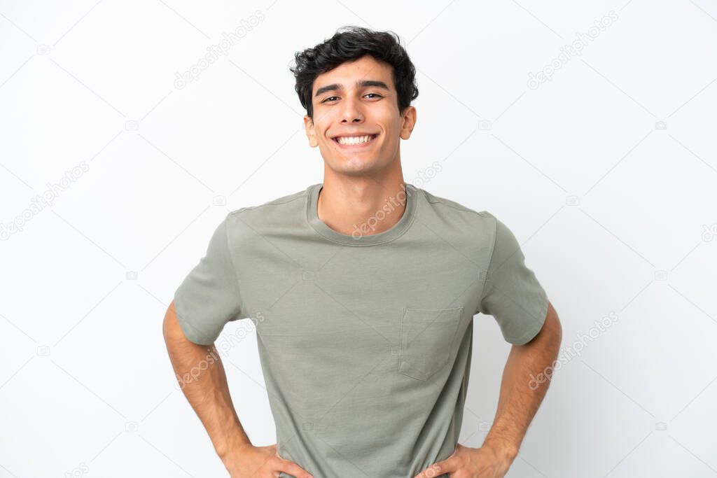 Young Argentinian man isolated on white background posing with arms at hip and smiling
