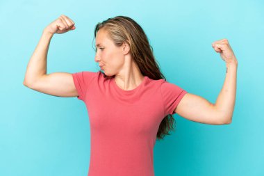 Mavi arka planda izole edilmiş beyaz bir kadın güçlü bir jest yapıyor.