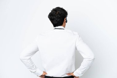 Tele pazarlamacı arka planda beyaz arka planda izole edilmiş bir kulaklıkla çalışıyor.