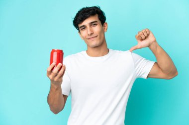 Arjantinli genç adam mavi arka planda kendini beğenmiş ve gururlu bir ferahlatıcı tutuyor.