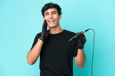 Dövme sanatçısı Arjantinli adam mavi arka planda ağzı açık bağırıyor.