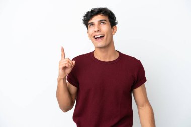 Beyaz arka planda izole edilmiş genç Arjantinli adam yukarı bakıyor ve şaşırıyor