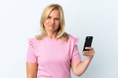 Üzücü bir ifadeyle beyaz arkaplanda izole edilmiş cep telefonu kullanan orta yaş