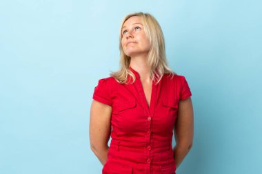 Mavi arka planda izole edilmiş orta yaşlı bir kadın var.