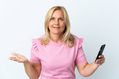 Beyaz arka planda izole edilmiş ve şok olmuş yüz ifadesi olan cep telefonu kullanan orta yaş