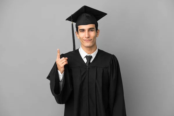年轻的阿根廷大学毕业生在灰色背景下与世隔绝 用食指指点点着一个伟大的想法 — 图库照片