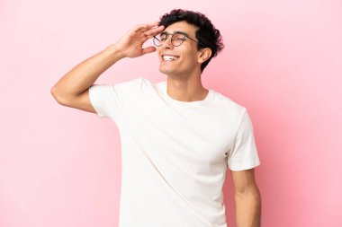 Arjantinli genç adam pembe arka planda izole edilmiş, gülümsüyor.