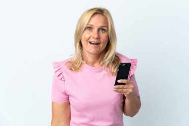 Beyaz arka planda izole edilmiş, şaşırmış ve şok olmuş bir yüz ifadesi olan orta yaş cep telefonu kullanımı