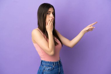 Mor arka planda yalıtılmış beyaz bir kadın, sürpriz bir ifadeyle işaret ederken...