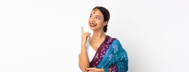 Beyaz arka planda izole edilmiş genç Hintli kadın harika bir fikre işaret ediyor.