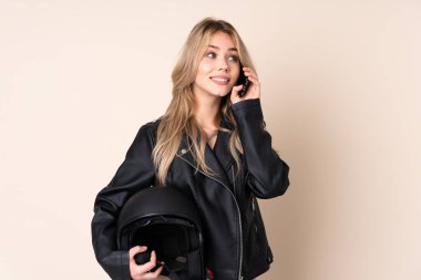 Motosiklet kasklı Rus kız bej arka planda izole edilmiş cep telefonuyla sohbet ediyor.
