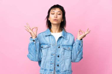 Genç Uruguaylı kadın Zen pozunda pembe arka planda.