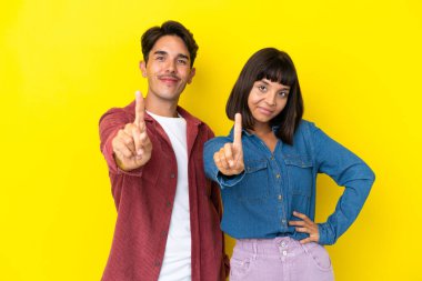 Sarı arka planda izole edilmiş genç ve melez bir çift parmak kaldırıyor.