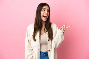 Pembe arka planda izole edilmiş genç beyaz kadın çözümü bulmak için parmağını kaldırıyor.