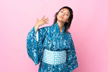 Kimono giyen genç bir kadın soyutlanmış mavi arka plan, yorgun ve hasta bir ifade.