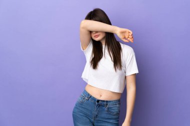 Genç Ukraynalı bir kadın mor arka planda izole edilmiş, gözleri elle kapatılmış.