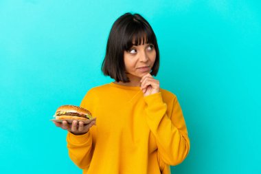 Genç esmer kadın izole edilmiş arka planda bir burger tutuyor.