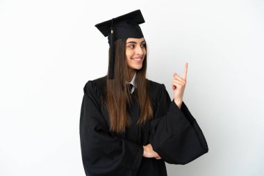 Beyaz arka planda izole edilmiş genç üniversite mezunu harika bir fikre işaret ediyor.