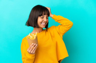 İzole edilmiş mavi arka planda patates kızartması tutan genç esmer kadın bir şey fark etti ve çözüme niyetlendi.